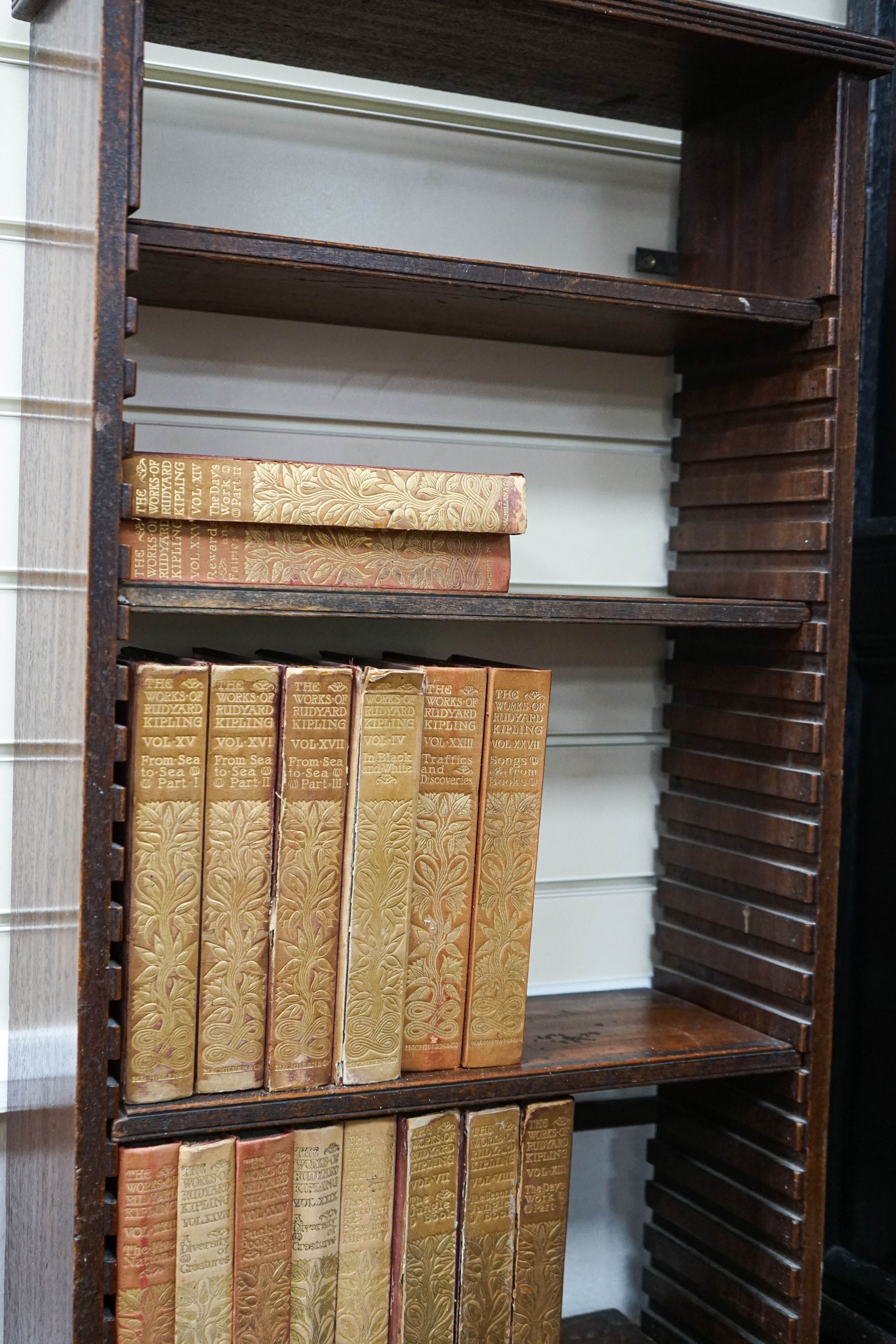 A Georgian mahogany wall-mounted narrow bookshelf, width 48cm, depth 18cm, height 147cm, containing a limited edition Works of Rudyard Kipling in 33 volumes, published 1900